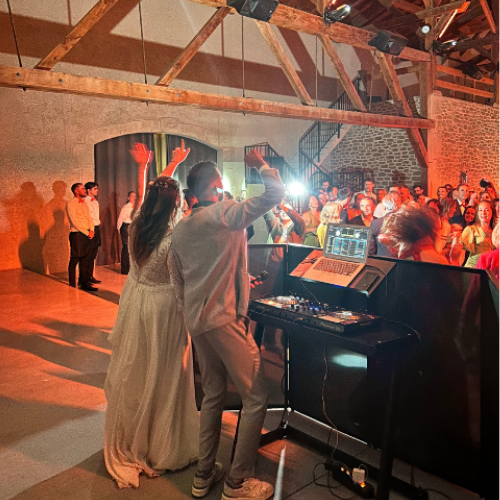 DJ professionnel anime une soirée de mariage dans une salle en pierre avec les mariés et leurs invités en fête